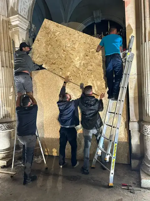 Artisans ADP Habitat posant de nuit un grand panneau de contreplaqué sur une entrée