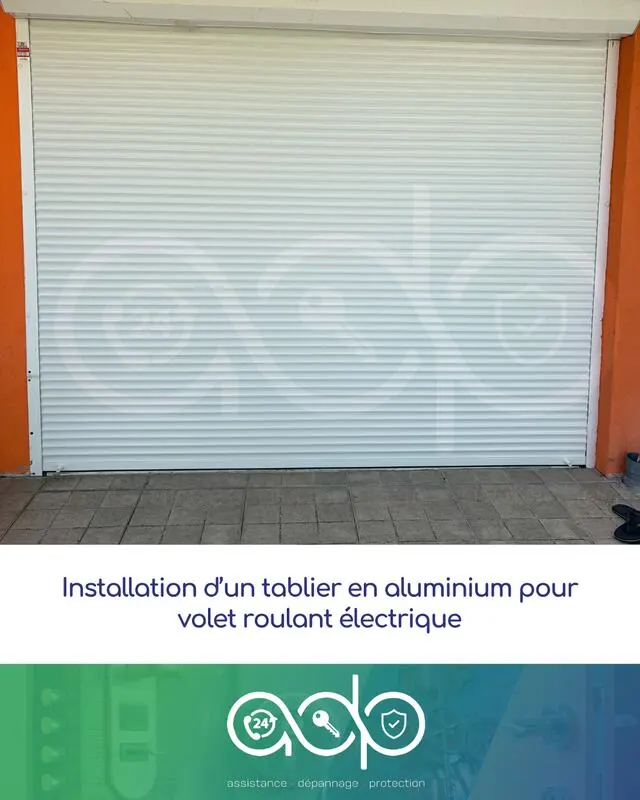 Volet roulant électrique à tablier aluminium blanc, posé sur un garage à façade orange.